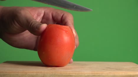 Eine-Hand,-Die-Durch-Eine-Tomate-Auf-Einem-Chroma-Hintergrund-Schneidet