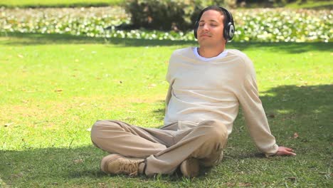 young man listening to music on the grass