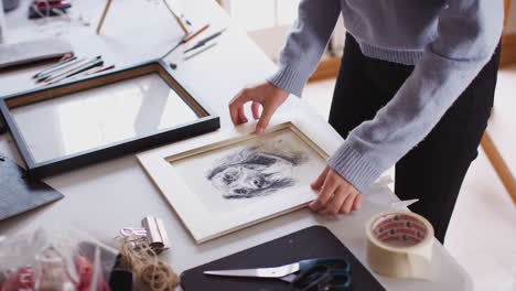 close up of female teenage artist framing picture in studio