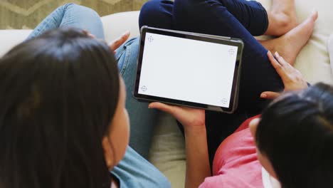 Biracial-sisters-sitting-on-sofa-and-using-tablet-with-copy-space,-in-slow-motion