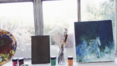 close up of paintings, paints and brushes in studio, slow motion