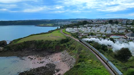 a steam train locomotive on the south devon railway passing through the coastal cliffside of paignton, torbay, devon