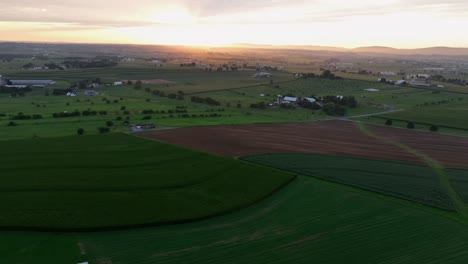agricultural farm fields on hills in rural area of america. epic golden sunrise at horizon. summer season in suburb district with farmsteads and large properties in united states