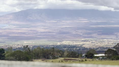 Cinematic-booming-up-shot-from-an-old-wooden-fence-overlooking-Maui-Valley-with-West-Maui-and-Maalaea-Bay-in-the-distance-on-the-island-of-Maui-in-Hawai'i