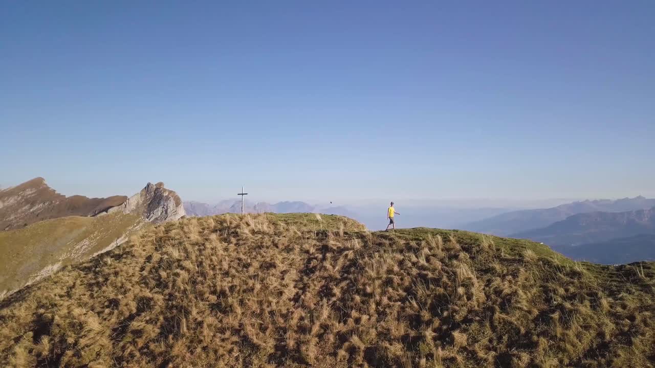 el dron orbita lentamente alrededor de un joven excursionista con una camisa amarilla en octubre