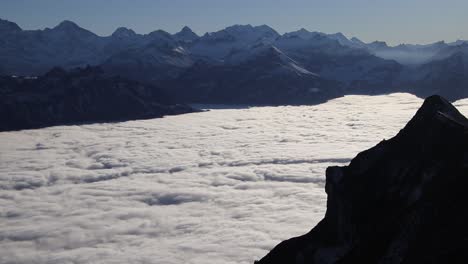 timelapse of fast moving fog with snowy swiss mountains and sunny weather above