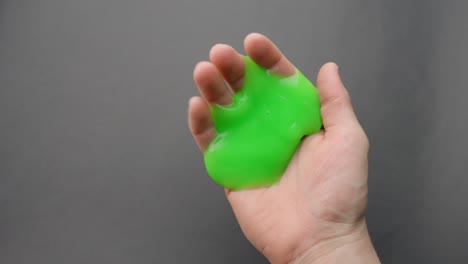 green slime slowly oozing through fingers in a close-up of a hand indoors