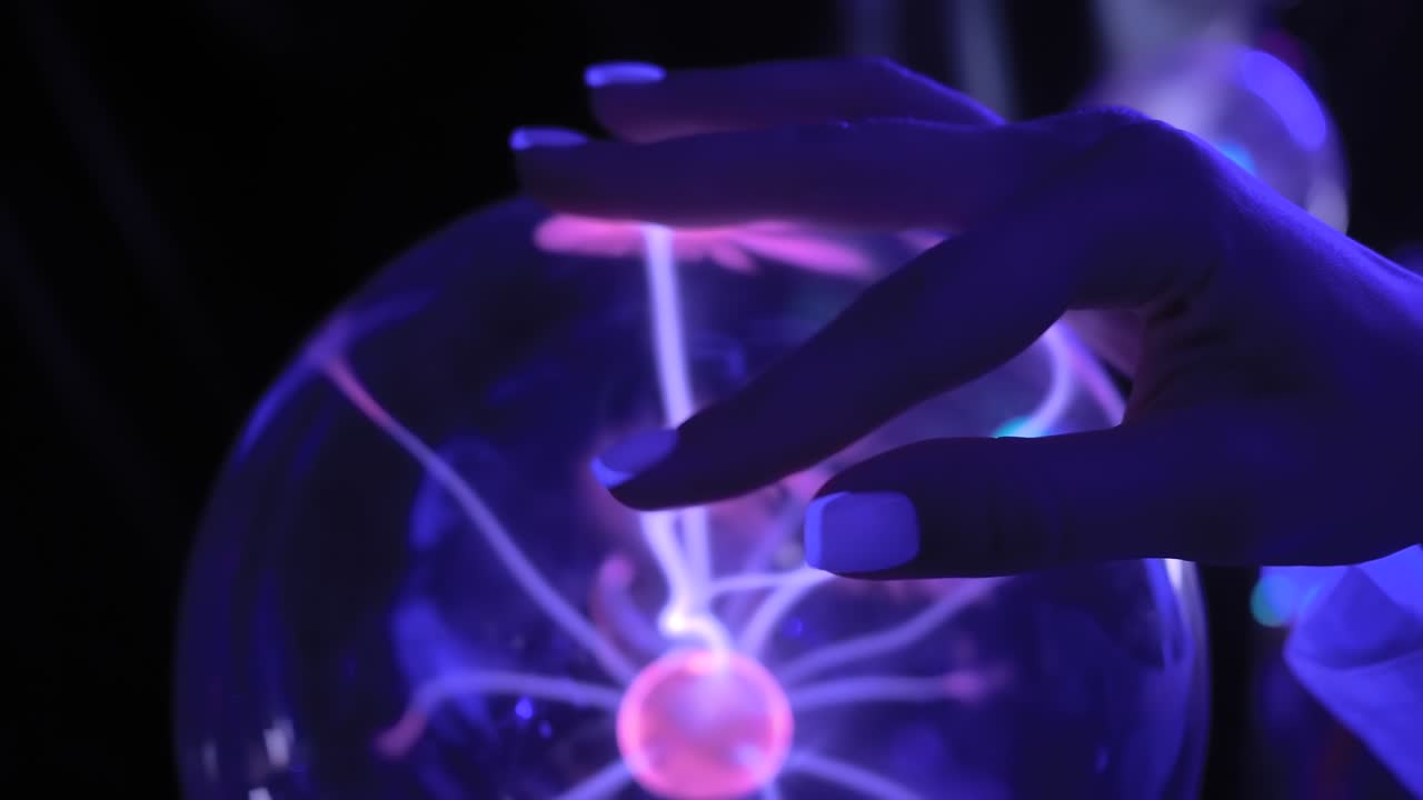 la mano de la mujer tocando la bola de plasma con muchos rayos de energía en el interior - de cerca