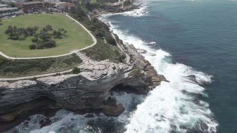 Olas-Rompiendo-Contra-La-Entrada-Rocosa-Y-Los-Acantilados-De-La-Península-De-Mackenzies-Point-En-Tamarama,-Nsw,-Australia