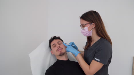 doctor injecting botox into the forehead of a male patient lying on a stretcher in a medical clinic.