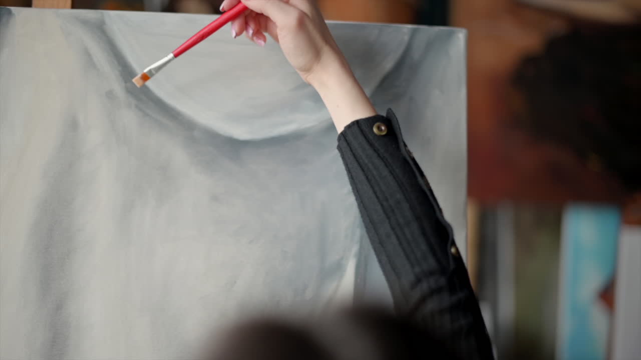 Close up of a woman painting a female body on a canvas at an art gallery workshop