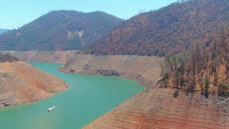 Inquietante-Antena-Sobre-El-Lago-Oroville-De-California-Azotado-Por-La-Sequía-Con-Bajos-Niveles-De-Agua,-Costa-En-Retroceso-Y-Gran-Cruce-De-Puentes