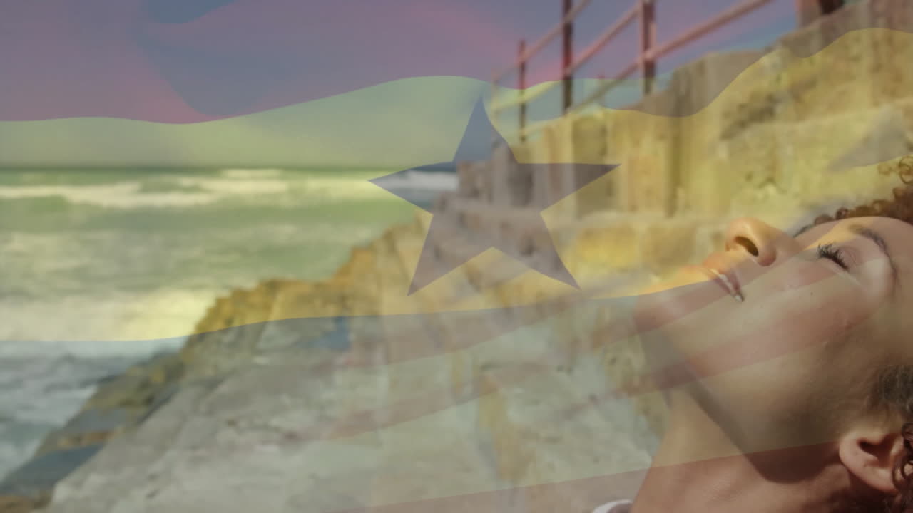 Sunlight bathing woman by ocean, Ghana flag animation overlay in background