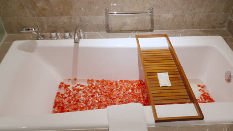 luxury hotel spa bathroom bathtub with flower petals inside decorated with marble tiles - push in