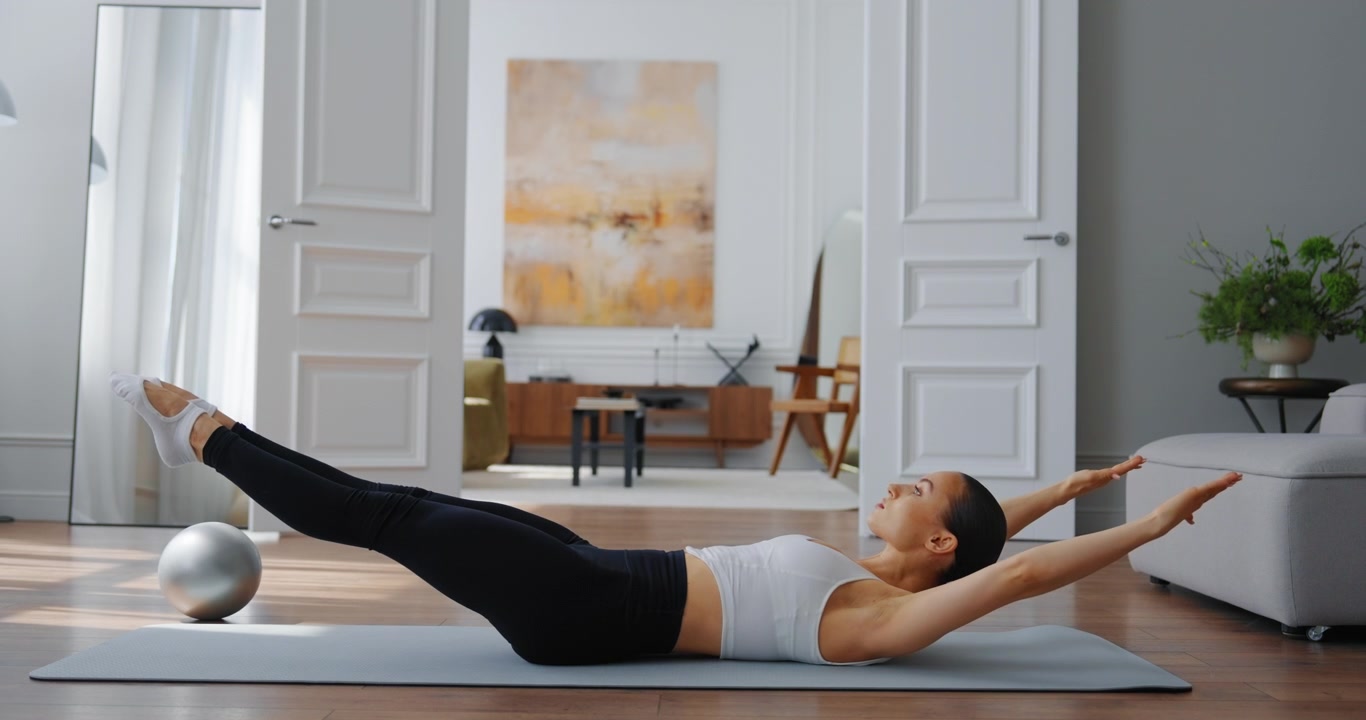 Young Woman Performing Pilates Core Exercises on a Mat at Home