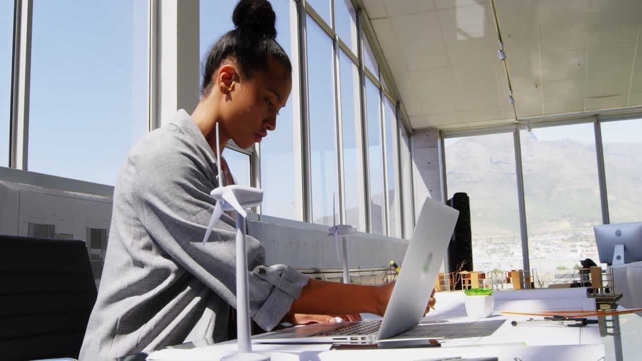Side view of African American Businesswoman using laptop at desk in a modern office 4k