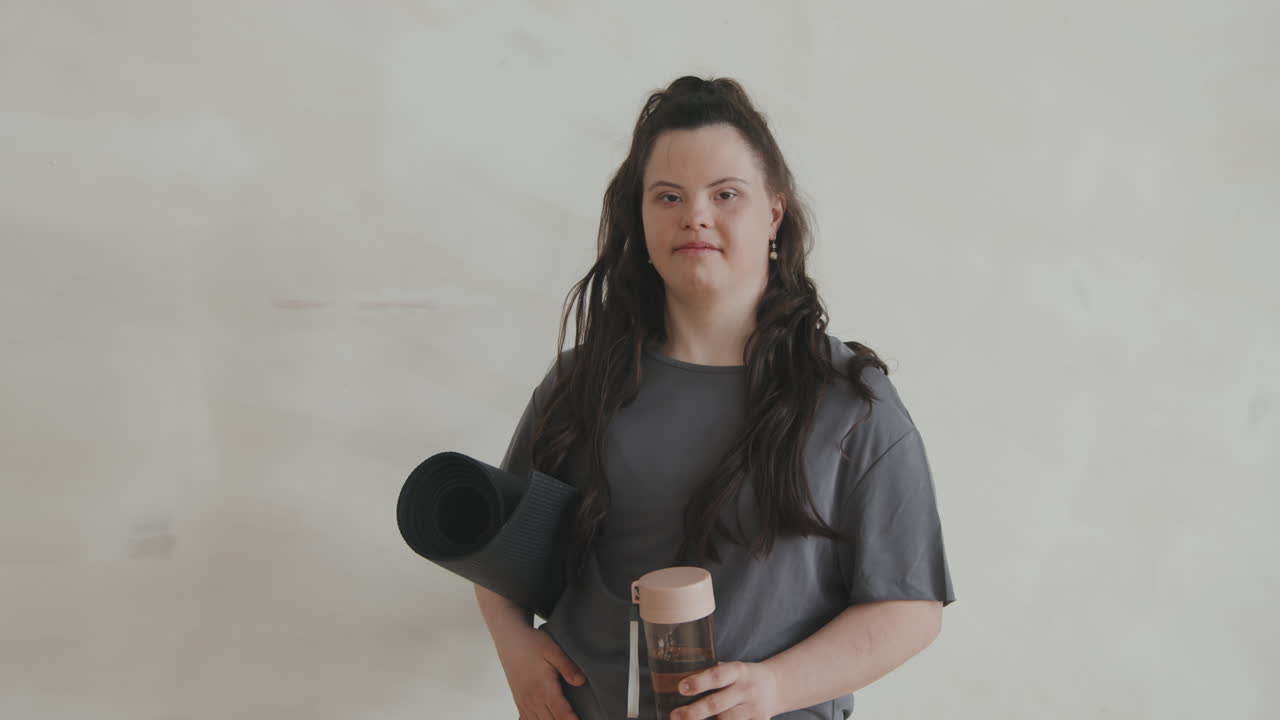 Portrait Of Woman With Down Syndrome Holding Yoga Mat And Sport Bottle