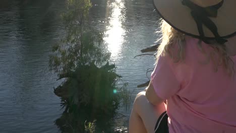 mujer rubia de naturaleza al aire libre sentada en el borde del río con un camping rosa