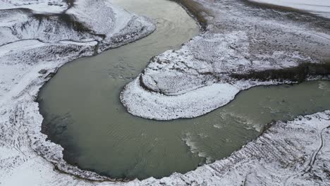 A-winding-river-in-the-north-of-Iceland-during-the-winter-with-snow,-aerial