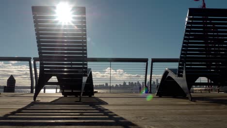 sun flares streaming through deck chairs overlooking harbor and cityscape