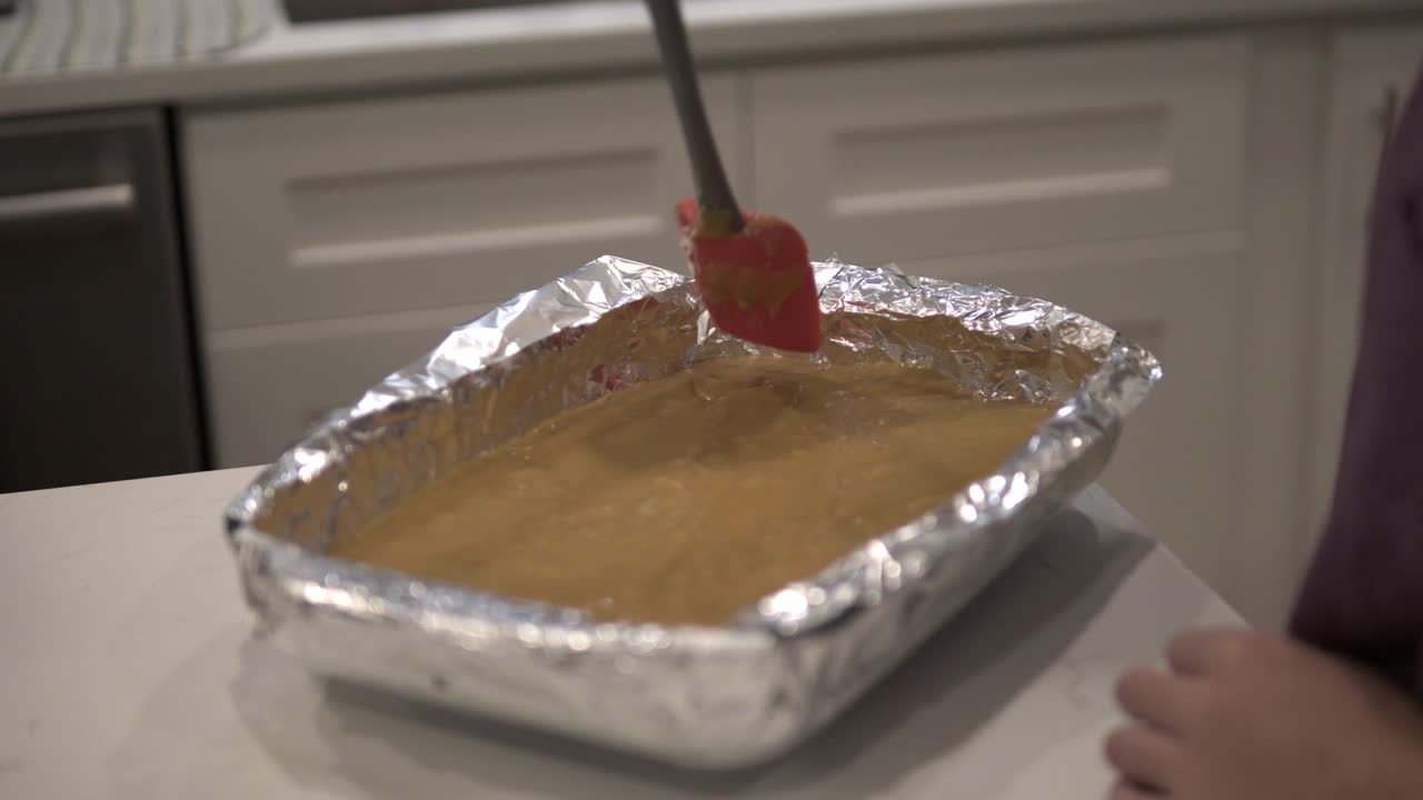 una niña nivela y suaviza la capa de mezcla de caramelo de galletas de mantequilla millonarias