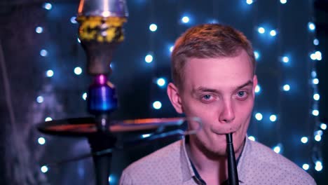 man smoking hookah in a nightclub