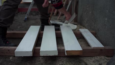 A-Man-is-Applying-Paint-to-the-Wood-Intended-for-the-Construction-of-a-Greenhouse-in-Indre-Fosen,-Norway---Close-Up