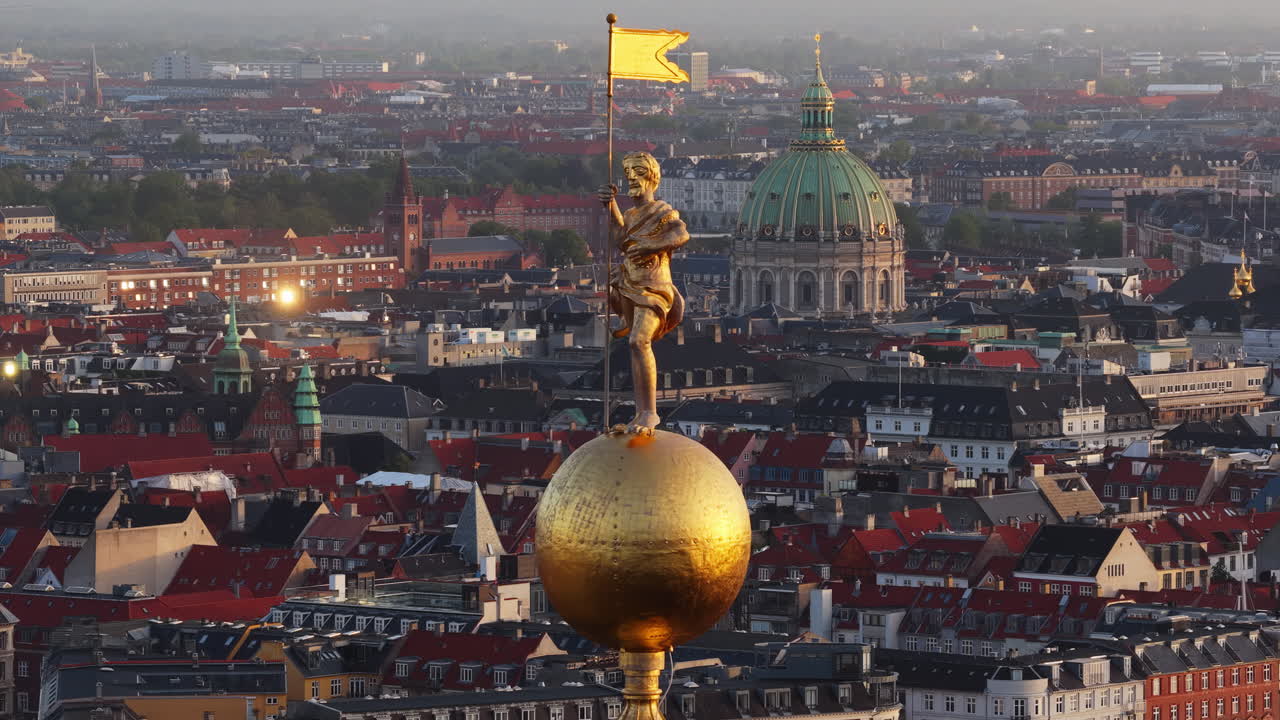 Aerial drone view of the golden statue atop a sphere on the Church of Our Saviour overlooking the Copenhagen skyline, with Frederik's Church dome in the background in Denmark