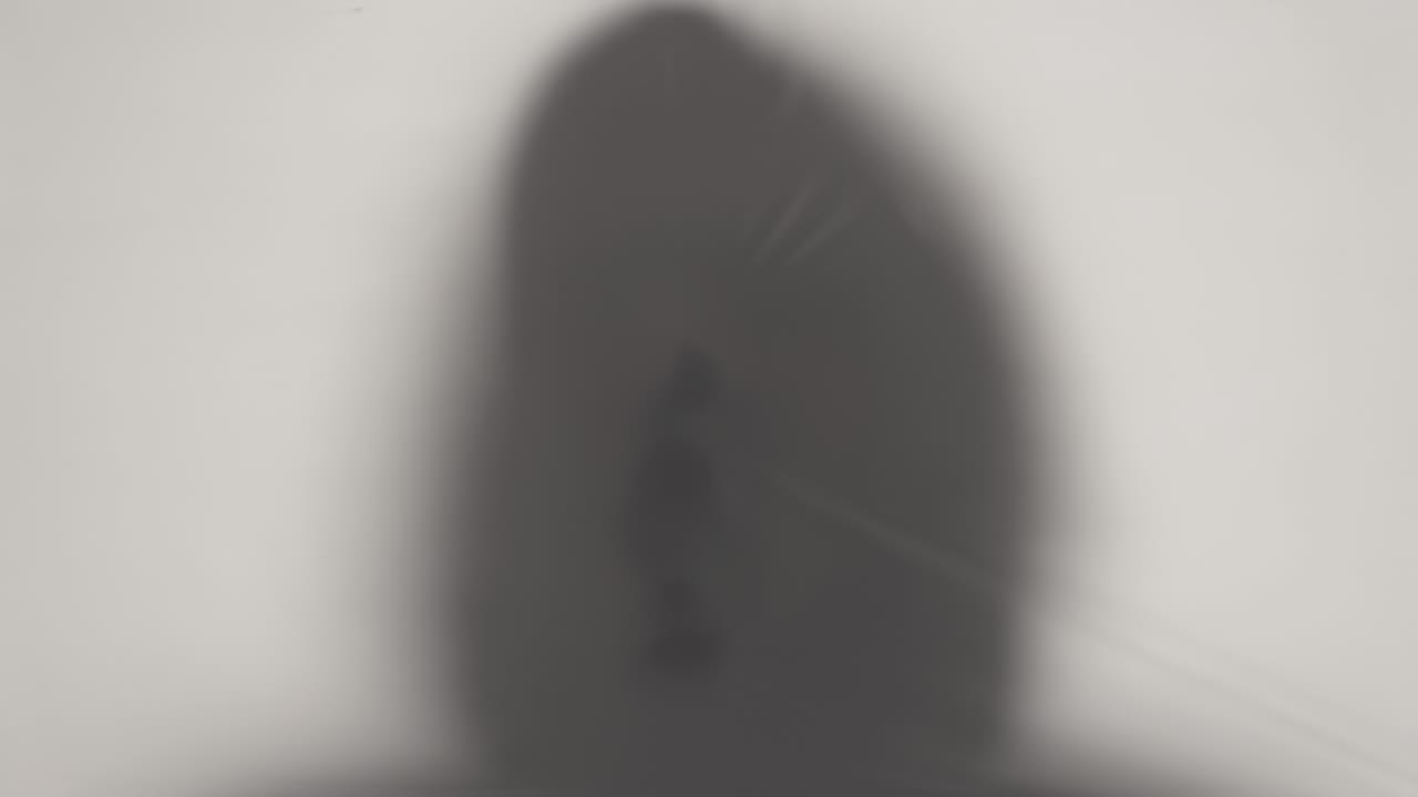 silueta en primer plano de la cabeza de un humano encapuchado rompiendo a través de celofán translúcido. ideas sobre el otro mundo, víctimas de violencia, paranormalidad, fantasmas. bucle de video 4k con efecto de rampa de velocidad.