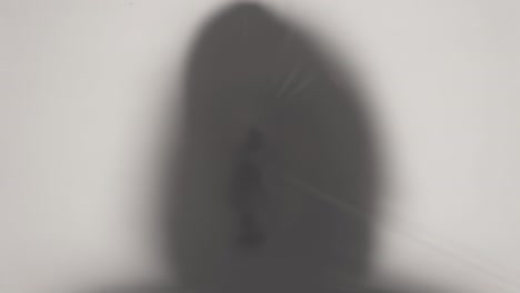 close-up silhouette of a hooded human's head breaking through translucent cellophane. ideas about the other world, victims of violence, paronormality, ghosts. 4k video loop with speed ramp effect.