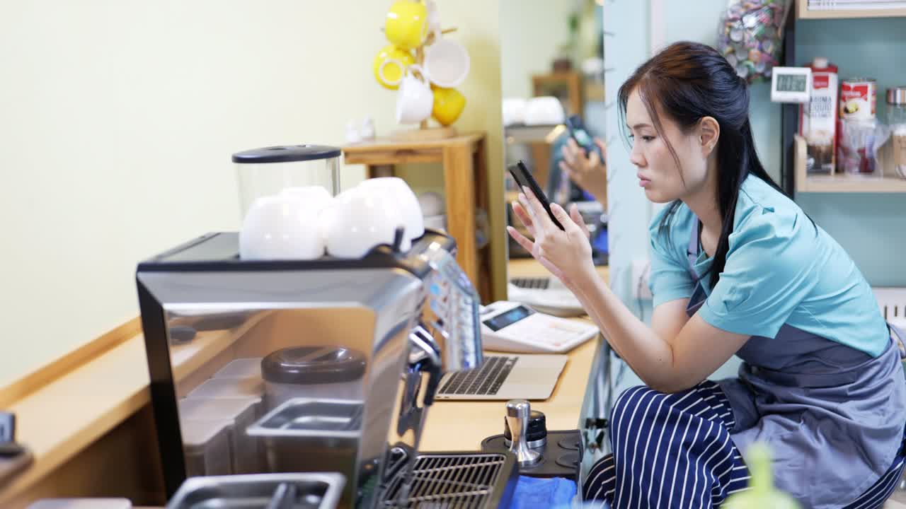 레스토랑 매니저가 커피에서 웹을 서핑하고 스마트폰으로 대화하고 있습니다.