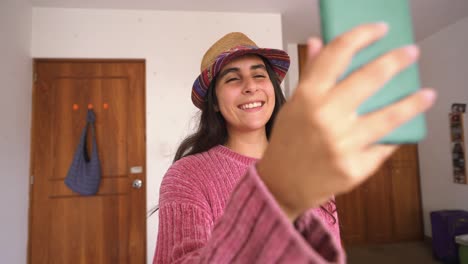 young woman laughing on video call using mobile phone in her room