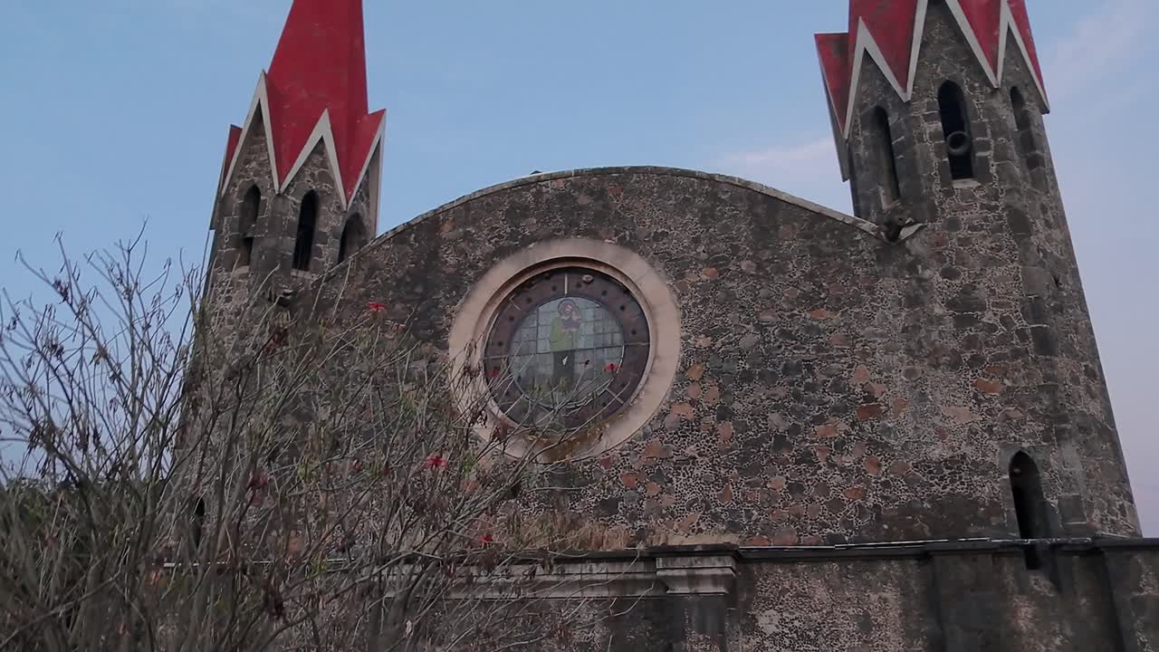 close-up of the facade of the Cuernavaca church with a beautiful window visible and a dry tree in front