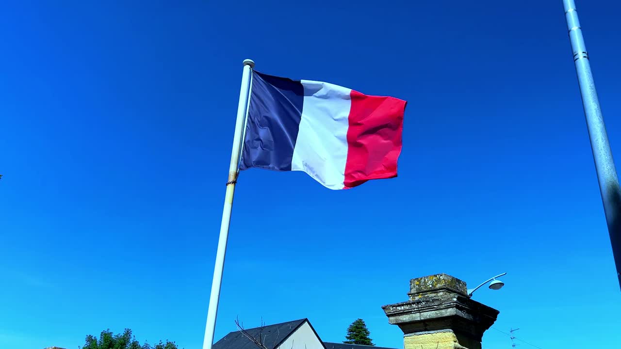 Bandiera francese che si srotola lentamente al vento contro un cielo blu per mostrare l'intera bandiera