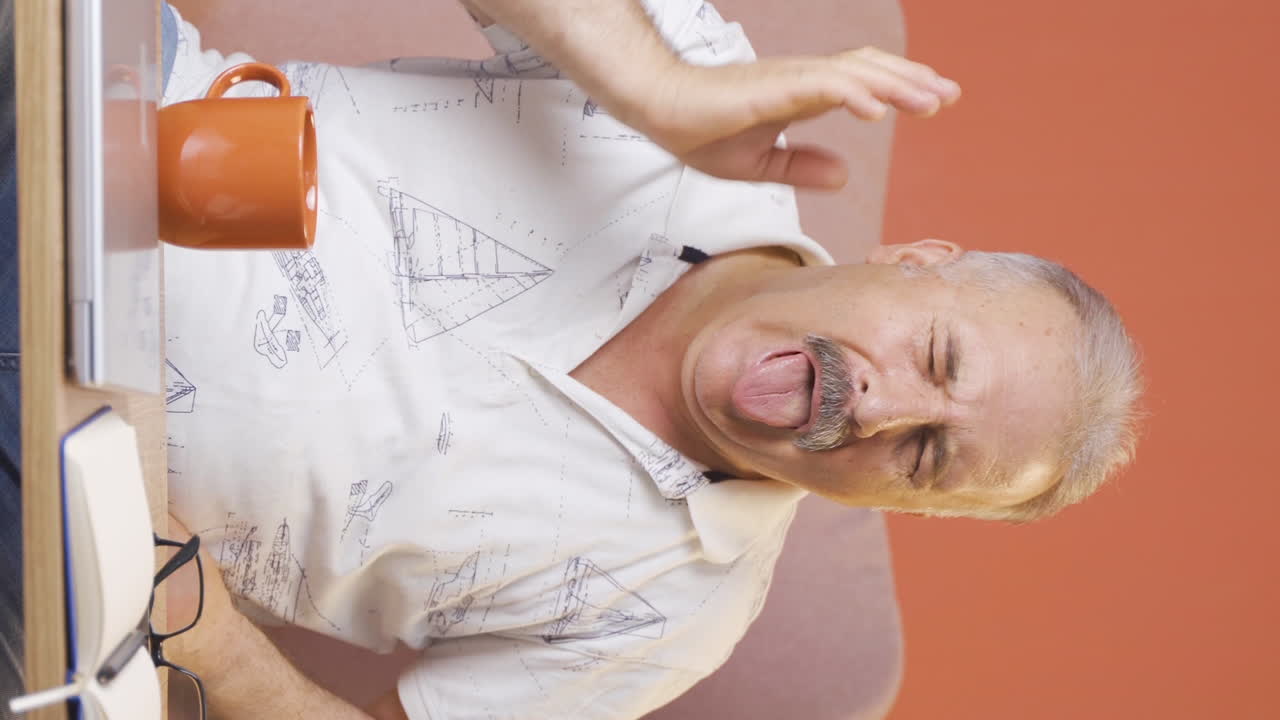 Vertical video of The old man's mouth is burning from the hot drink.