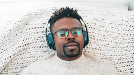 man relaxing with headphones on a blanket