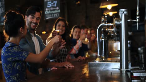 friends toasting with drink at bar counter