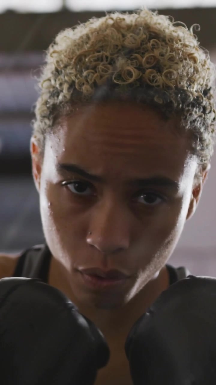 Vertical video: Female boxer jabbing with gloves for training, dotted panel shifting with code