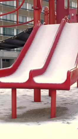 red slides covered in fresh snow at empty urban playground evoking childhood winter memories