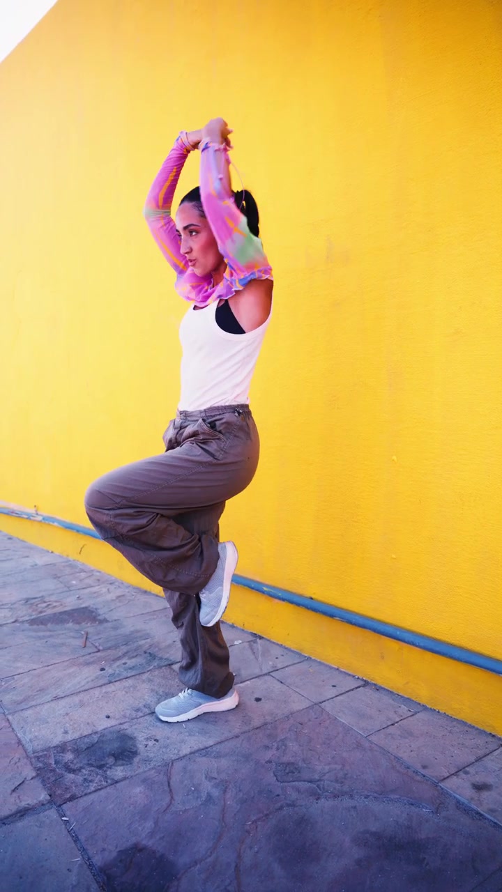 Young Woman Dancing Against a Vibrant Yellow Wall