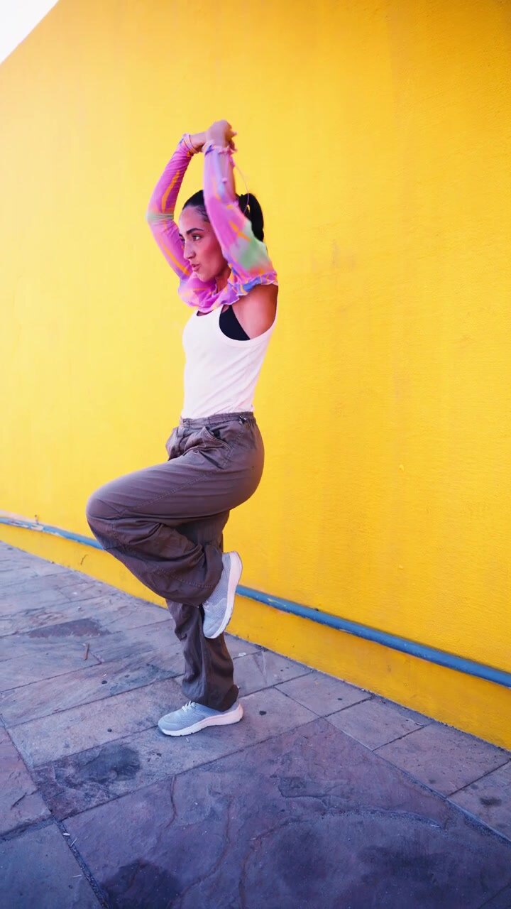 Young Woman Dancing Against a Vibrant Yellow Wall