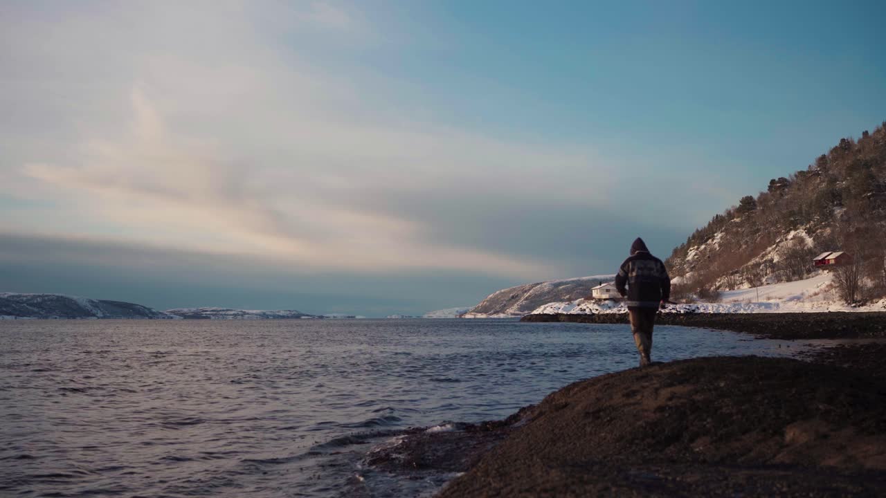 Un uomo è andato a pescare da solo, lanciando la sua canna da pesca verso la riva del Trondheimsfjord, Trondheim, Norvegia