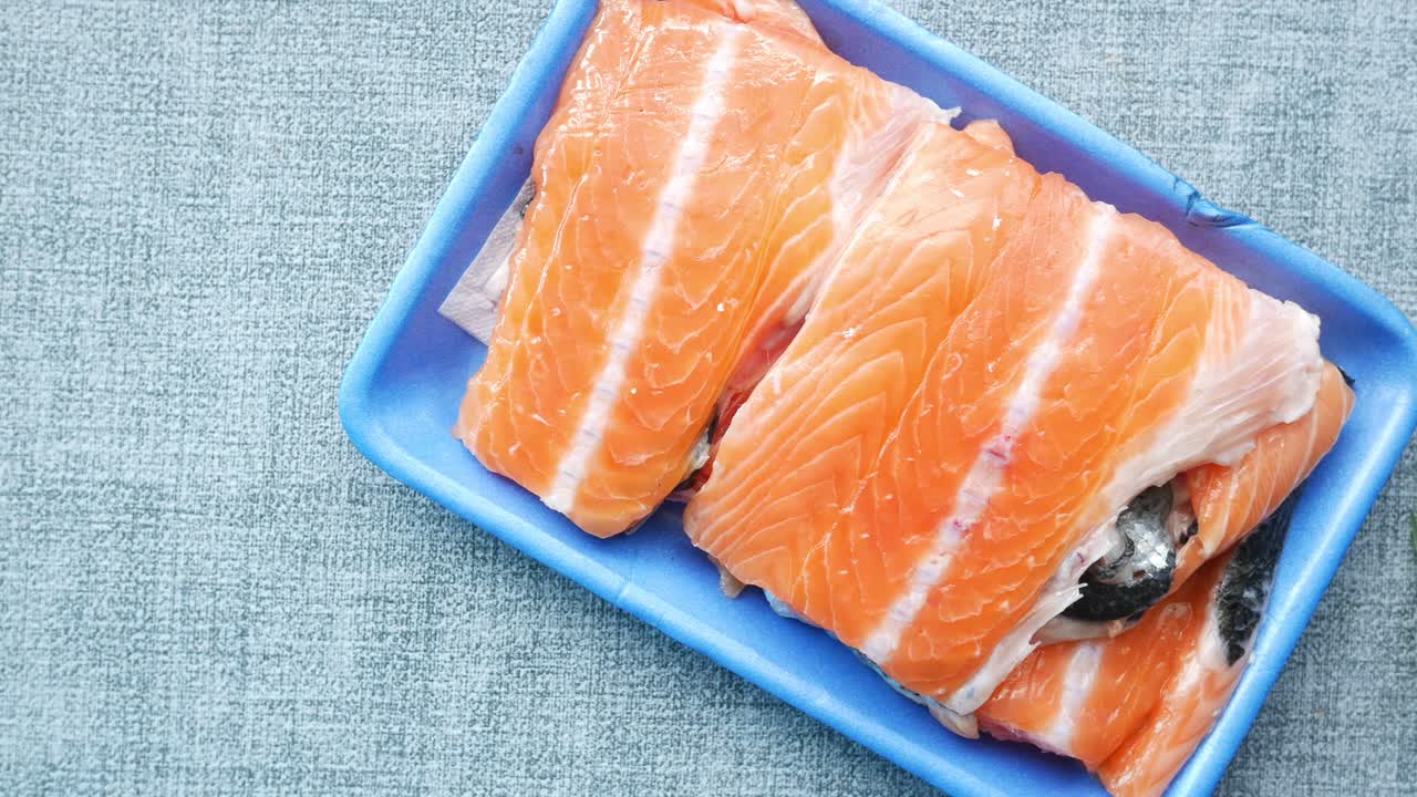 Trancio di salmone crudo e fresco su una confezione di plastica sul tavolo