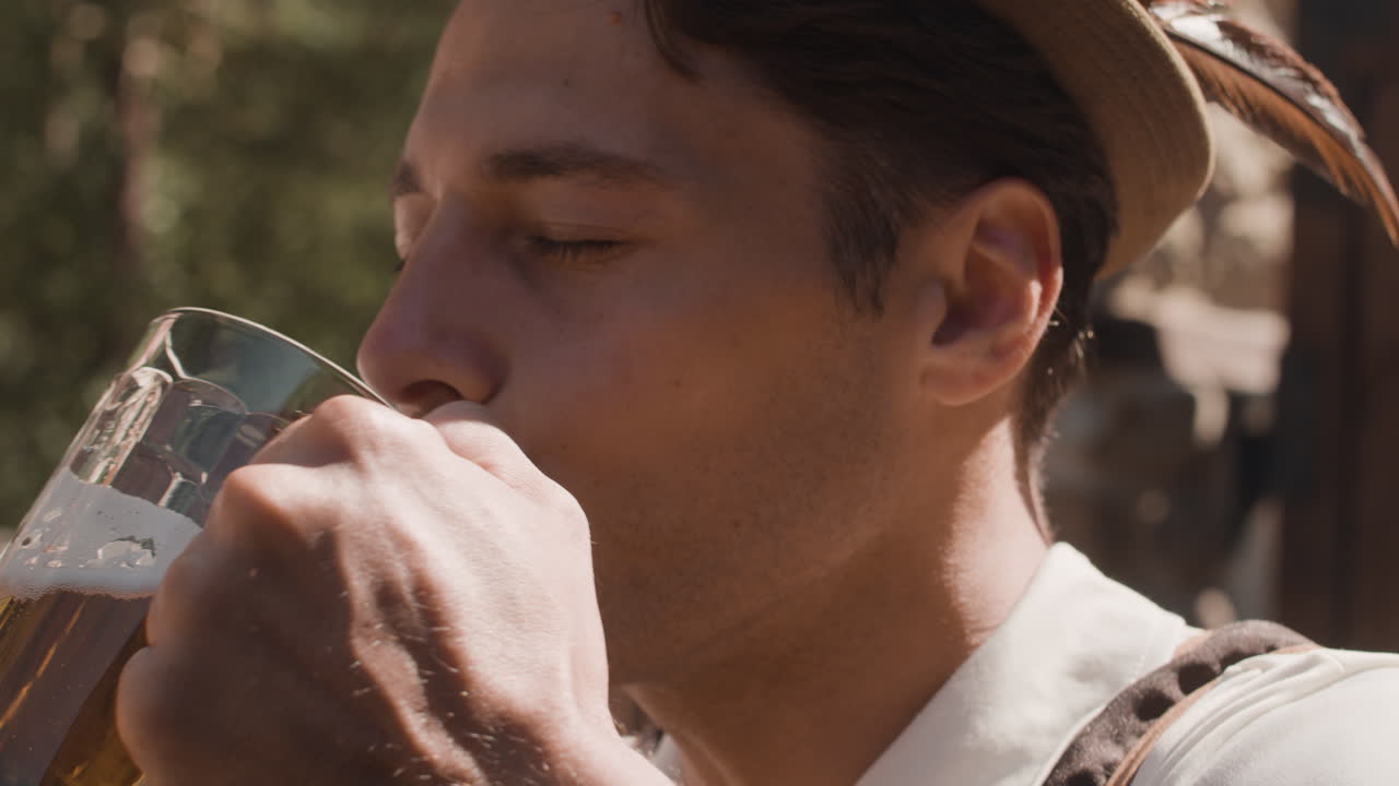 Man in traditional Bavarian clothing drinking beer