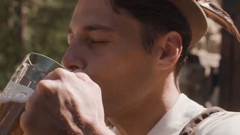 man in traditional bavarian clothing drinking beer