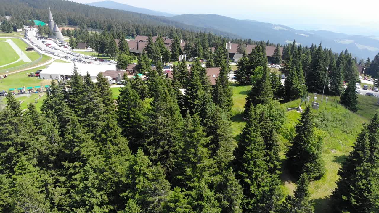 Hotel Rogla resort Slovenia with trailer park, resort area and soccer field during spring season, Aerial pan left reveal shot
