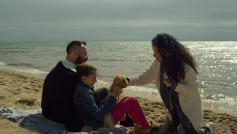 hermosa familia relajarse en la playa juntos por el agua tranquila. la gente tomando fotos con la cámara