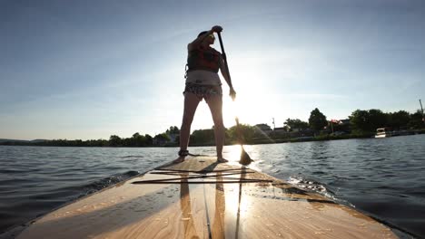 Mujer-En-Forma-Paddle-Boarding-Pov-Retroiluminado