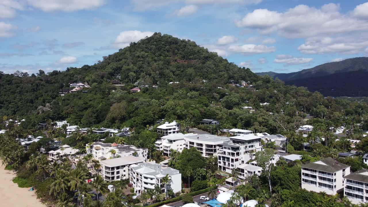 4K Aerial view of a beachside town with hotels and a mountain in the background in North Queensland Australia