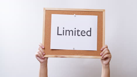 Woman's-hand-shows-the-paper-on-board-with-the-word-Limited-in-white-studio-background-with-copy-space